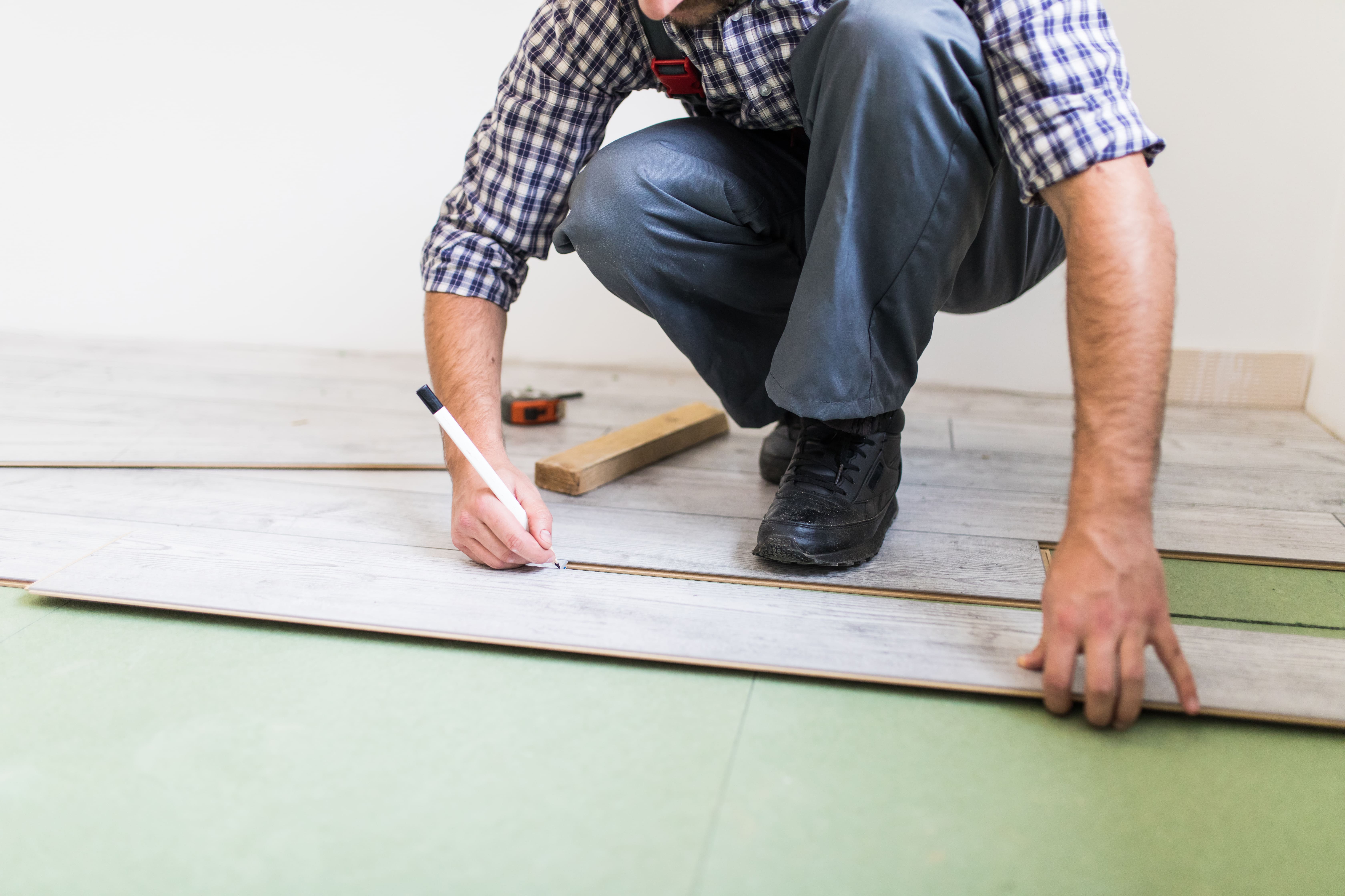Young worker laying a floor with bright laminated flooring boards